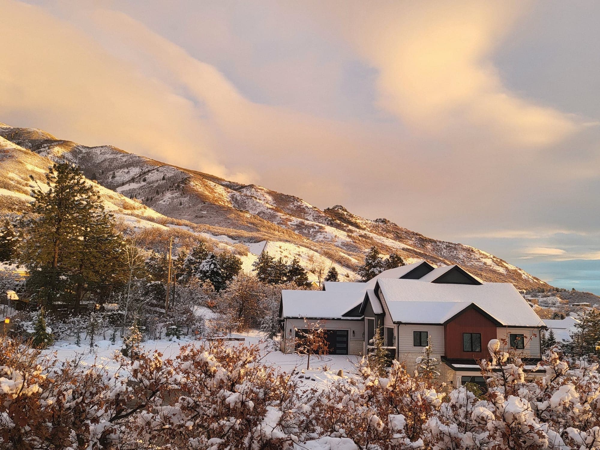 A modern home on snowy Wasatch foothills at sunset