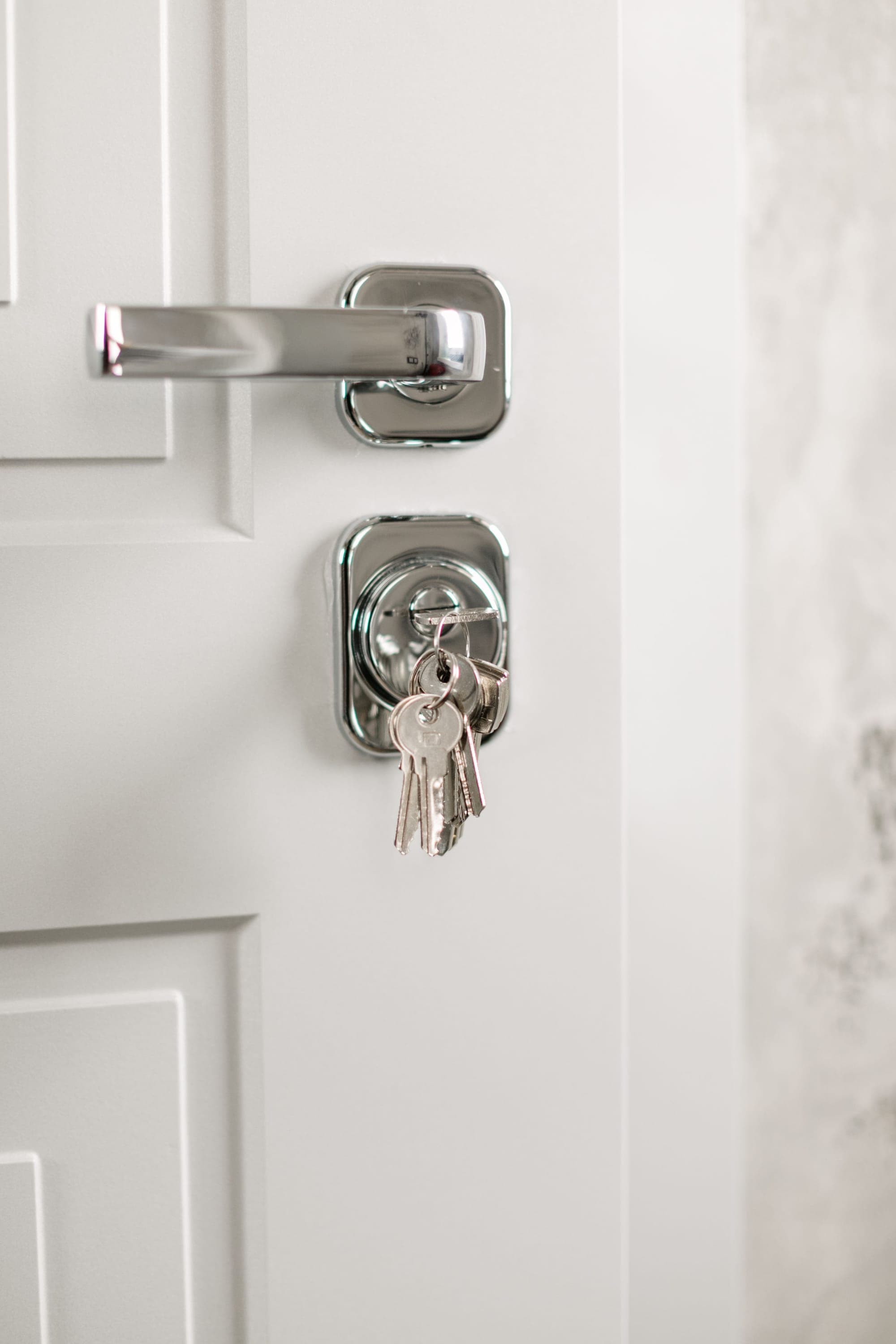 House keys hanging from a lock in a white door